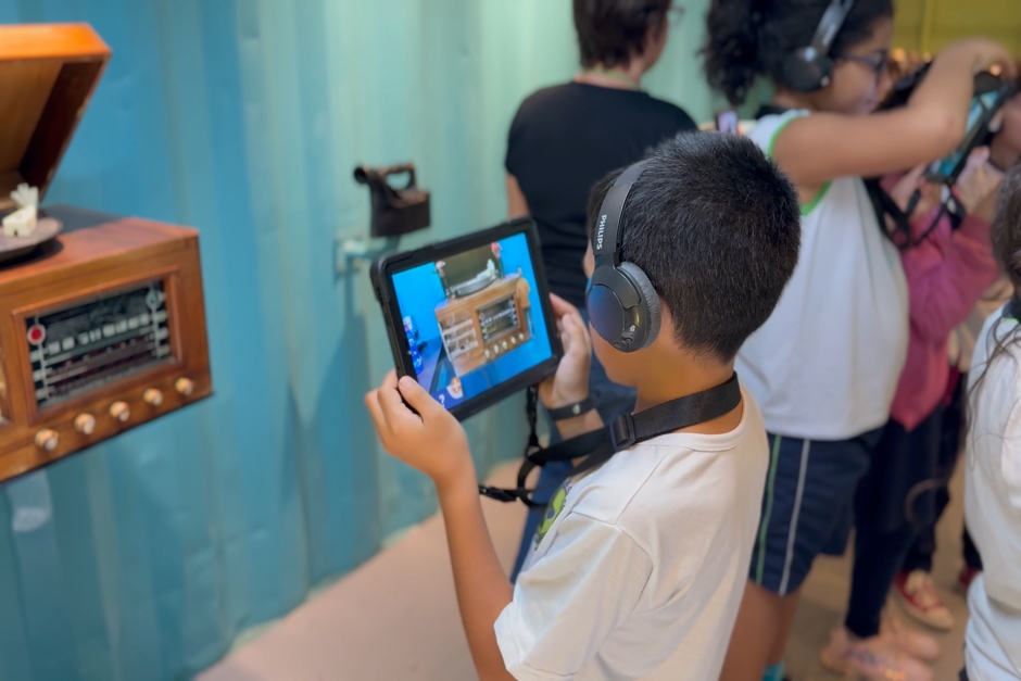 Garoto utiliza tablet interagindo com peça do Museu do Lixo