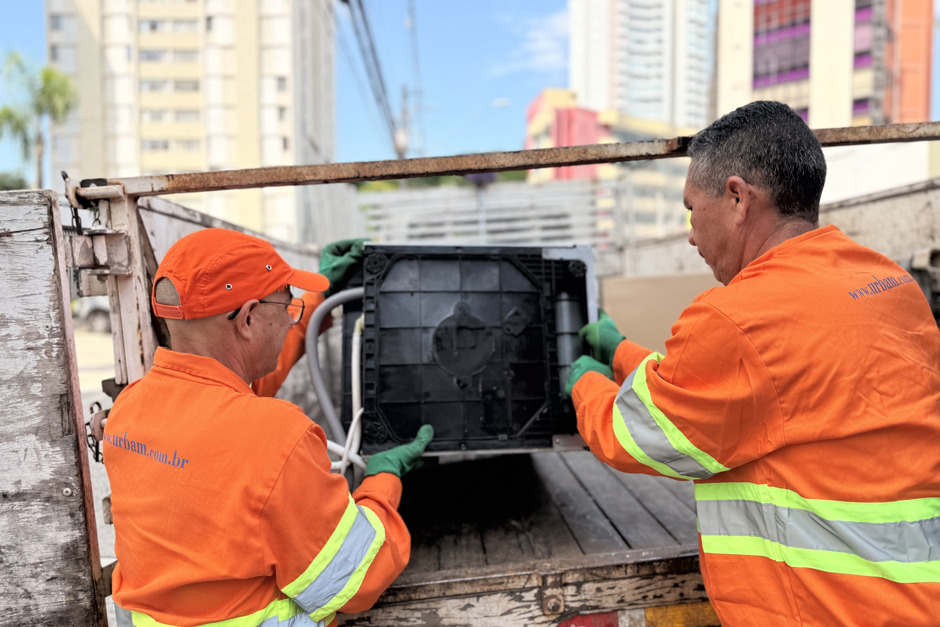 Dois colaboradores da Urbam posicionam uma máquina de lavar no caminhão da equipe de coleta de resíduos eletrônicos