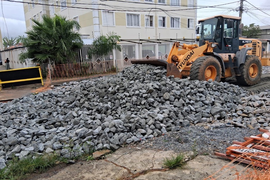 Trator laranja fecha a grande erosão da rua com muitas pedras